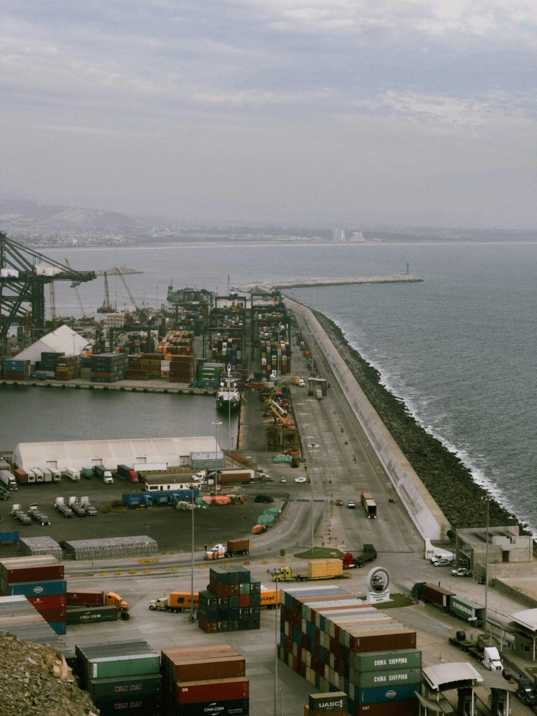 Drone aerial view of active seaport in Baja California, with trucks, containers, and cargo ships.