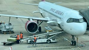 Airplane being loaded with cargo at the airport terminal with ground crew.