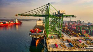 A bustling aerial view of a container port in North Jakarta, Indonesia with ships and cranes.